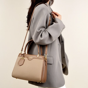 Detailed side view of two-tone PU leather crossbody bag with dual handles and strap