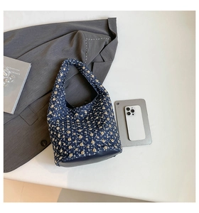 Detailed close-up of dark blue denim bucket bag with decorative metallic silver studs