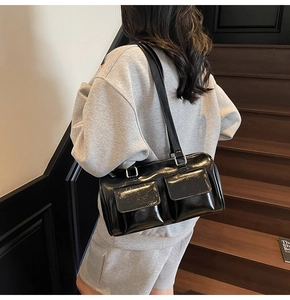 Street style shot of black glossy leather underarm bag with double front pockets detail