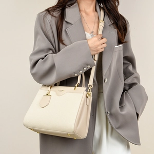 Detail of a beige contrast tote bag showing fine fabric texture and golden buckles
