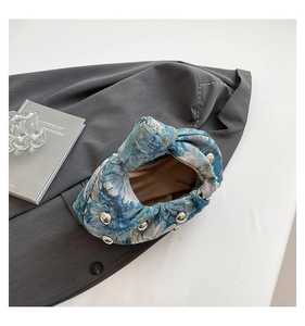 Detail of blue jacquard fabric with silver rivets and unique knotted handle design
