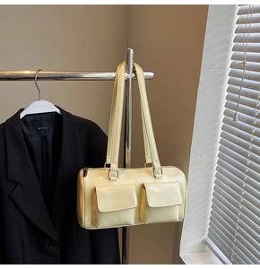 Detail of cream yellow leather cylinder bag with utility pockets and metal zipper