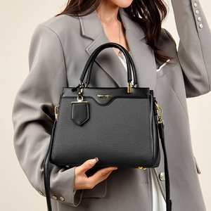 Detail of classic black handbag showing fine leather texture and golden hardware accents