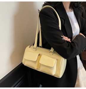 Detail of creamy yellow shoulder bag with double front pockets on a model in suit
