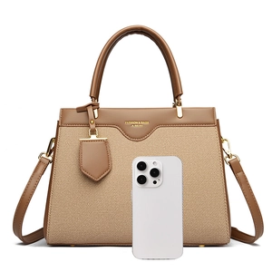 Detail of a brown leather and fabric handbag with gold hardware and phone for scale