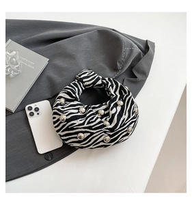 Macro detail of zebra print fabric handbag featuring silver beads and knotted handle design