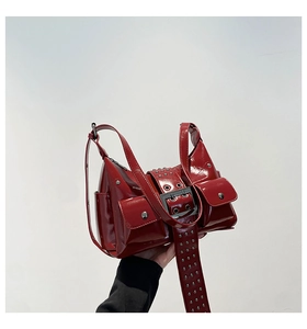 Detailed close-up of red patent leather motorcycle bag with silver rivets and metal buckles