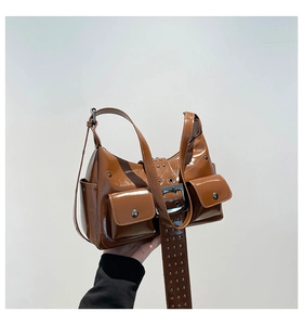 Detail of brown patent leather underarm bag with silver rivets and buckle straps