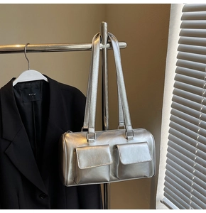 Detailed view of silver metallic shoulder bag with double front pockets on garment rack