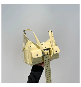Detail of pale yellow punk style handbag featuring metal rivets and buckle accessories