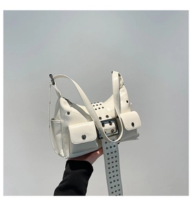 Detail of cream patent leather handbag with metal buckle and punk rivet accents