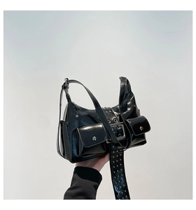 Detail of black glossy faux leather shoulder bag with silver rivets and buckle