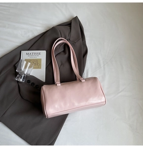 Detail of light pink faux leather underarm bag on a grey blazer showing glossy texture