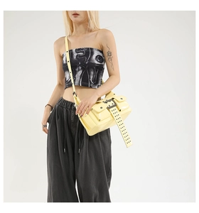 Detail of cream patent leather Y2K crossbody bag with metal rivets and shoulder strap