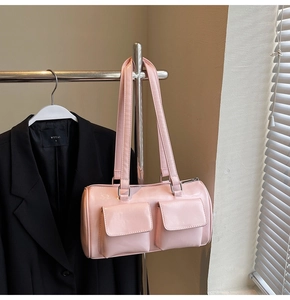 Detailed close-up of a pink glossy cylinder bag with twin front pockets and silver rings