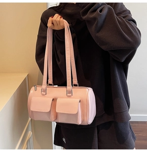 Detail of pink glossy patent leather Boston bag with dual pockets and long handles