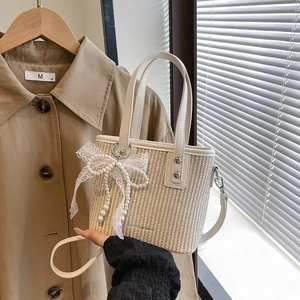 Beige woven bucket bag with pearl lace bow and adjustable shoulder strap for women