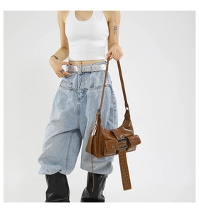Detail of dark brown vintage Y2K punk shoulder bag with rivets and multi-pocket design