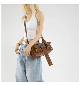 Detail of dark brown wax leather crossbody bag with silver rivet studs and large buckles