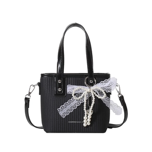Black woven shoulder bag with white lace bow, pearl pendant and top handle design