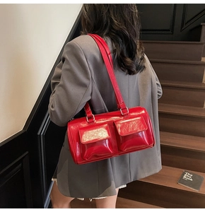 Close-up of red glossy leather shoulder bag with pockets shown on wooden stairs