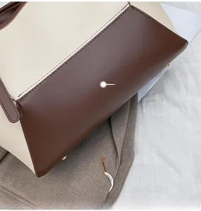 Détails des coutures renforcées et des pieds en métal doré sur le sac fourre-tout en toile