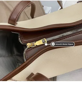 Détail de la fermeture éclair dorée lisse sur le cabas en toile crème et cuir marron