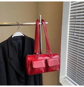 Detail of red cylindrical shoulder bag with front square pockets and glossy finish