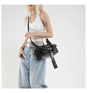 Close-up of black patent leather shoulder bag with silver rivets and Y2K aesthetic