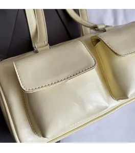 Close-up of cream faux leather pillow bag showing soft litchi texture and pocket detail