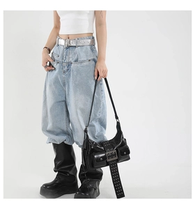Detail of black glossy motorcycle shoulder bag featuring metal rings and punk rivet design
