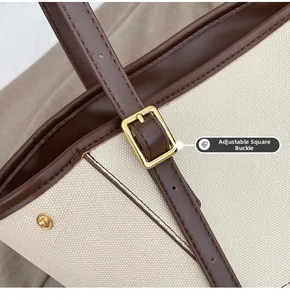 Détail de la boucle dorée réglable sur le sac fourre-tout en toile beige et cuir brun