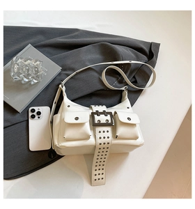 Detail of white Y2K style crossbody bag with silver studs and small buckle pockets