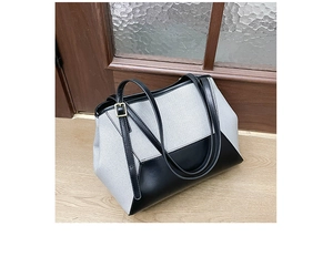 Détail du tissu gris et du cuir noir sur un grand sac cabas avec boucle dorée en métal
