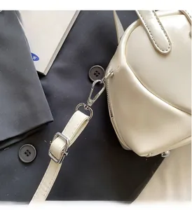 Macro detail of silver hardware and adjustable strap on a cream PU crossbody bag