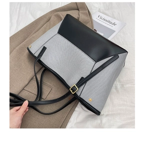 Détail du sac cabas contrasté avec texture toile et finitions en cuir noir élégantes