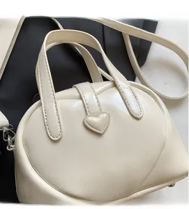 Detail view of heart-shaped stitching and buckle on cream PU leather handbag