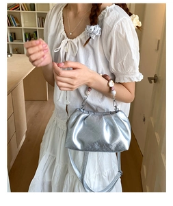 Detail of silver metallic cloud bag with colorful beaded handle and pleated texture