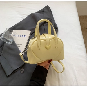 Detail of light yellow heart PU handbag with elegant heart-shaped buckle and fine stitching