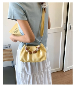 Detailed view of yellow ruched cloud bag with decorative marble pattern beads