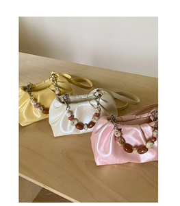 Detail of pleated cloud bags in yellow, white, and pink with marble beaded handles