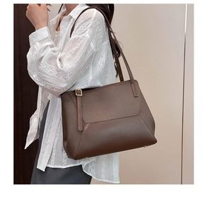 Détail du cabas en cuir marron foncé avec boucle dorée réglable et texture haut de gamme