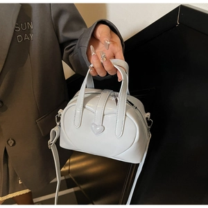 Close-up of light blue patent leather handbag with stitched heart detail and sleek handles