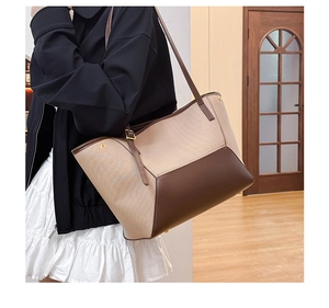 Détail d'un grand cabas en toile beige avec bordure en cuir marron porté au quotidien