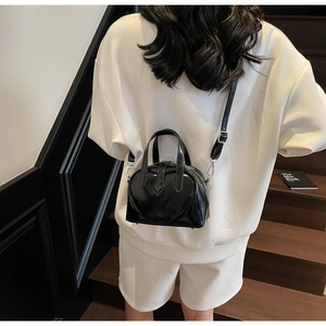 Crossbody view of black heart-embossed PU leather shell bag on a model side