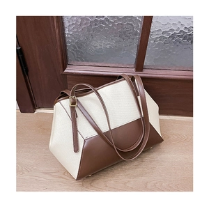 Détails des coutures contrastées, sangles en cuir et boucles dorées sur un grand sac cabas