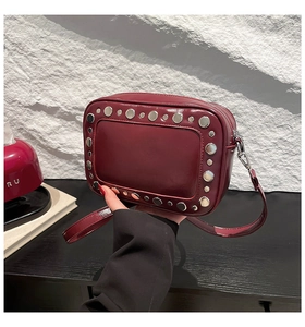 Dettaglio della superficie lucida in ecopelle bordeaux e dei rivetti in argento
