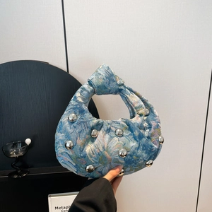 Blue floral hobo bag with knotted handle and silver studs on textured fabric