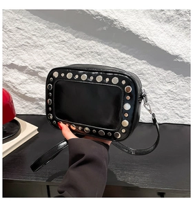 Dettaglio di borchie argentate su borsa a tracolla in pelle lucida nera con zip