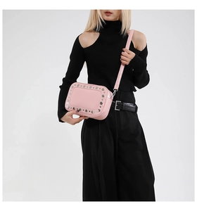 Borsa a tracolla retrò rosa con borchie argentate e sottile tracolla su sfondo bianco